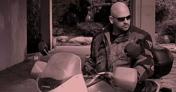 Black and white photo of man sitting on a motorcyle